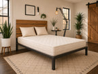 Bedroom with a bed featuring a wooden headboard and organic latex mattress, surrounded by decorative plants and a lamp.