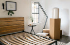 Bed frame before a mattress is placed on it. Organic latex mattress arrived by mail and is roll-packed in a box next to the bed.